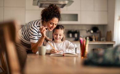 A,Mother,Helps,Her,Young,Daughter,Complete,Homework,In,A