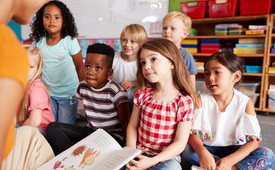 Group,Of,Elementary,School,Pupils,Sitting,On,Floor,Listening,To